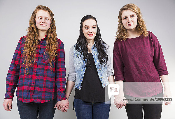'Three young women holding hands committed to teamwork; Alberta  Canada'