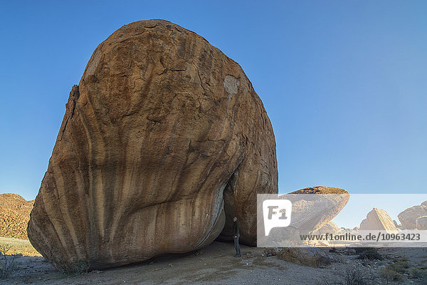 'Person standing under a large boulder in Richtersveld National Park; South Africa'