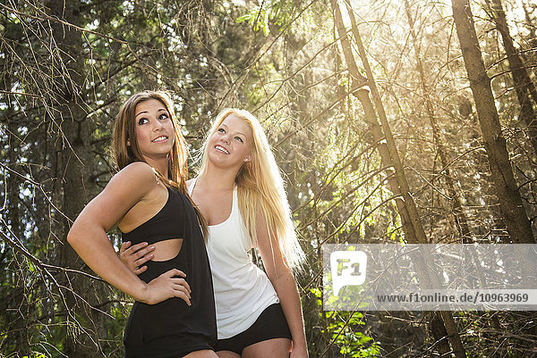 'Two girlfriends posing together in the woods in the sunshine; Edmonton  Alberta  Canada'