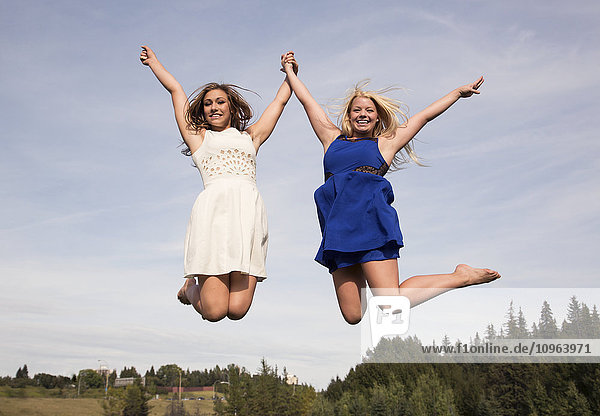Zwei jugendliche Sportler in Kleidern  die in einem Park hoch in die Luft springen; Edmonton  Alberta  Kanada'.