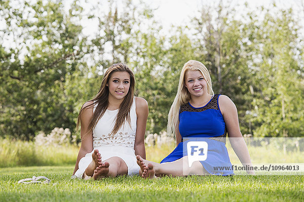 'Two girlfriends spending time together in a park in their dresses; Edmonton Alberta Canada'