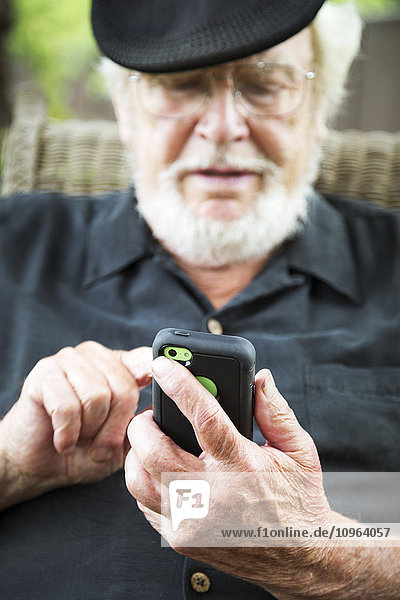Ein älterer Mann benutzt ein Smartphone; Maple Ridge  British Columbia  Kanada'.