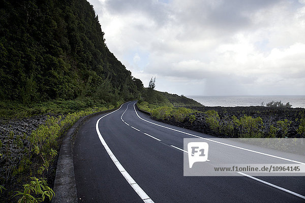 Straße am Meer unter einem dramatischen Himmel; Insel La Réunion  Frankreich'.