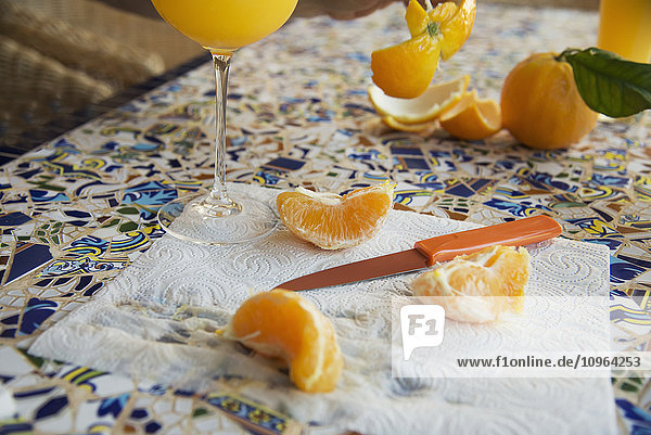 Geschälte und in Scheiben geschnittene Orange und ein Glas Orangensaft; Fornalutz  Mallorca .