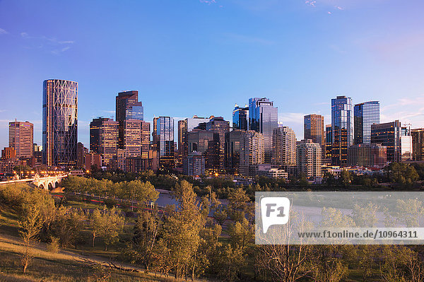 Moderne Stadtsilhouette bei Sonnenuntergang mit beleuchteten Wolkenkratzern; Calgary  Alberta  Kanada'.