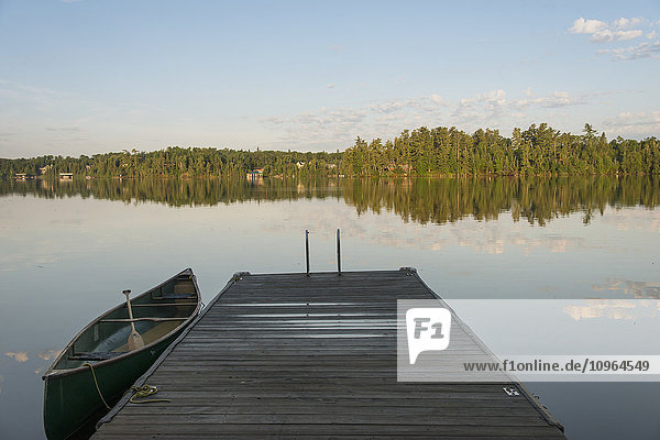 Kanu neben einem Holzsteg auf einem ruhigen See; Ontario  Kanada'.