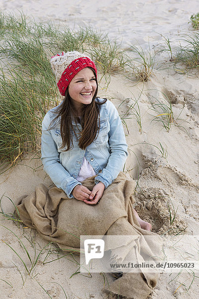 'A young woman sits on a beach wearing a knit hat; Tarifa  Cadiz  Andalusia  Spain'