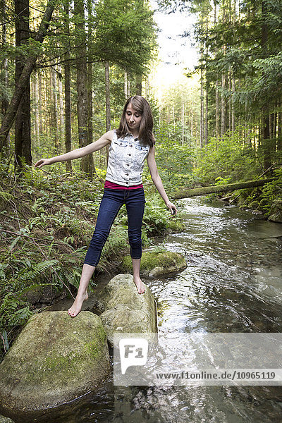 Teenager-Mädchen  das barfuß über Felsen in einem Bach läuft; Chilliwack  British Columbia  Kanada