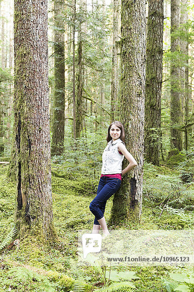 'Portrait of a teenage girl leaning against a tree in a forest; Chilliwack  British Columbia  Canada'