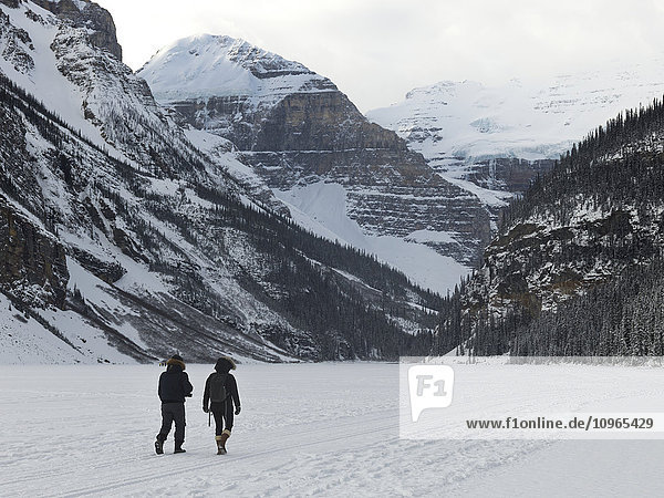 'People walking on frozen Lake Louise with a view of the snow covered mountains; Lake Louise  Alberta  Canada'