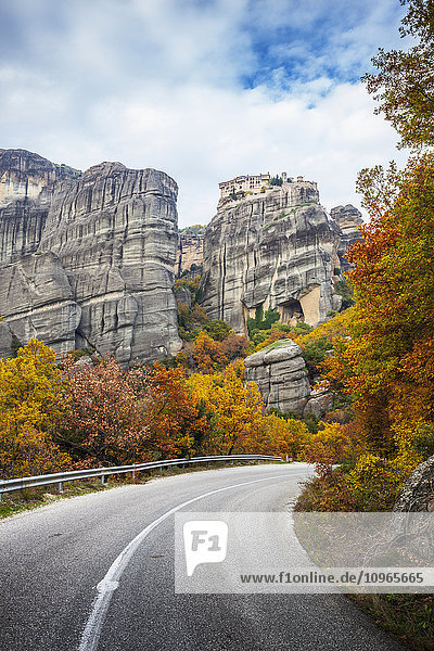'Monastery perched on a cliff  a road and autumn foliage; Meteora  Greece'