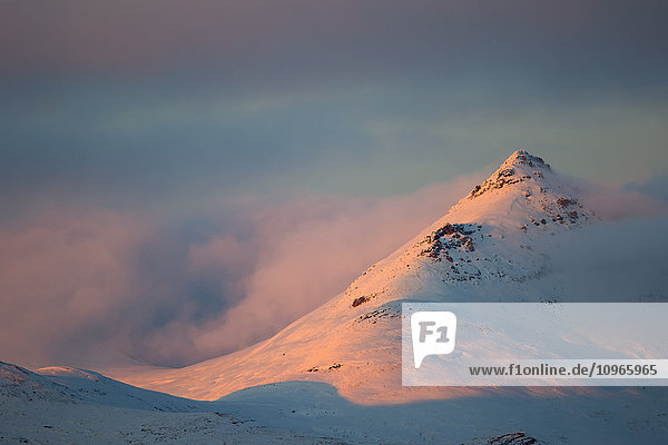'Light from the sunset illuminates the mountains along the Dempster Highway northern Yukon; Yukon Canada'