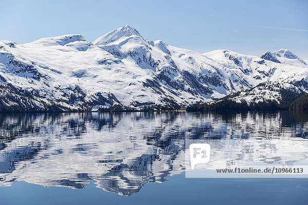 'Snow covered mountains reflect in the calm waters of Prince William Sound in winter  Kings Bay; Alaska  United States of America'