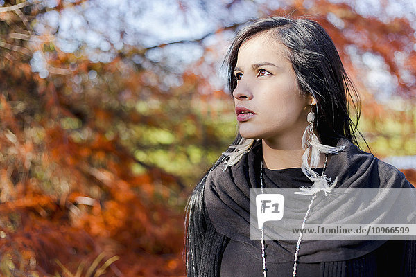 Ein junges weibliches Aborigine-Modell  das mit nachdenklichem Gesichtsausdruck in der freien Natur im Herbst posiert