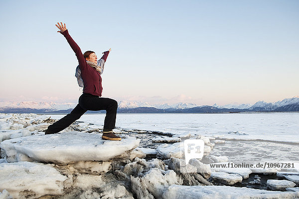 Frau übt Yoga auf einem Eisbrocken am Strand von Homer  Südalaska