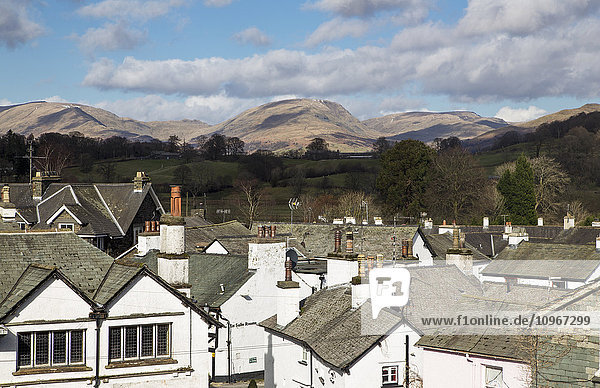 'White houses and rooftops with mountains in the distance; Hawkshead, England'