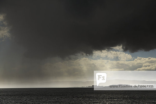 Regen fällt aus bedrohlichen dunklen Wolken über dem Wasser; Otter Ferry  Schottland'.