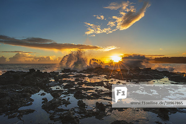 Wellen brechen bei Sonnenaufgang über einen Felsvorsprung; Kauai  Hawaii  Vereinigte Staaten von Amerika'.