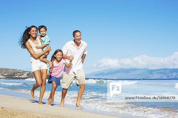 Happy Mixed Race Family of Four on the Beach