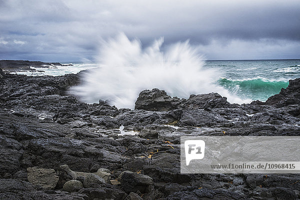 Eine Welle plätschert gegen die Felsen an der Südküste von Island; Island'.