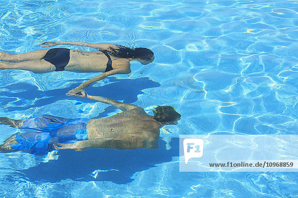 Ein Paar schwimmt unter Wasser in einem Pool  Saint Georges Caye Resort; Belize City  Belize'.