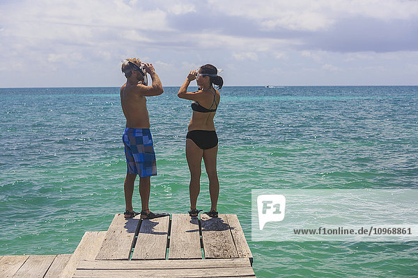 Ein Paar steht auf einem Holzsteg mit Schnorchelausrüstung  Saint Georges Caye Resort; Belize City  Belize'.