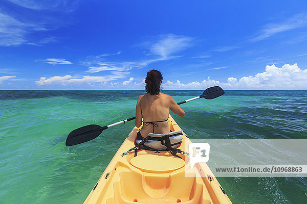 Eine Frau im Bikini in einem Kajak auf der Karibik  Saint Georges Caye Resort; Belize City  Belize'.