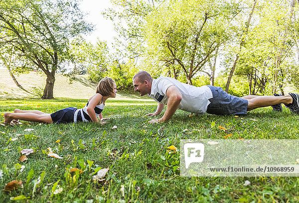 'A father and daughter staring each other down in a park during a family outing; Edmonton  Alberta  Canada'