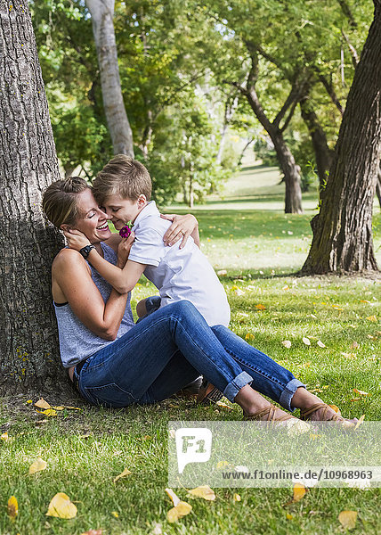 'Mother getting a flower from her son while spending quality time at a park during a family outing; Edmonton  Alberta  Canada'