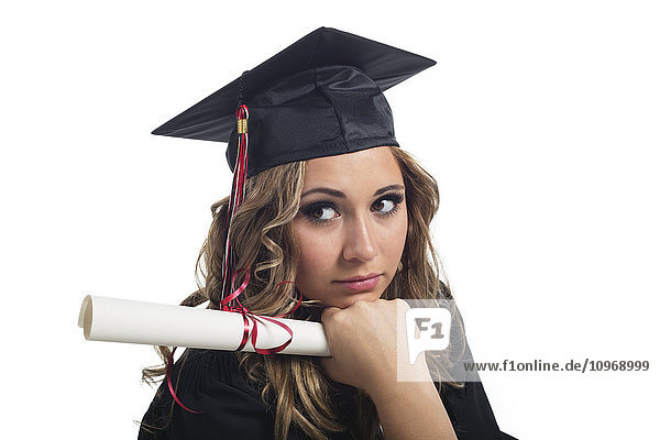 'Portrait of a young woman graduate holding her diploma and contemplating her graduation; Edmonton  Alberta  Canada'