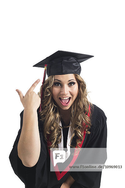 'Young graduating woman pointing at her grad cap in celebration; Edmonton  Alberta  Canada'