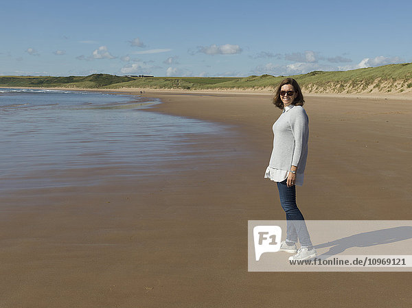 Frau mit Sonnenbrille am Strand von Cruden Bay an der Cruden Bay; Aberdeenshire  Schottland .
