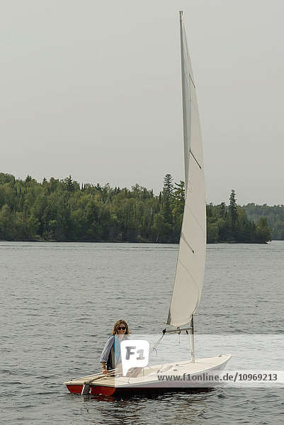 Eine Frau sitzt auf einem kleinen Segelboot auf einem See; Ontario  Kanada'.