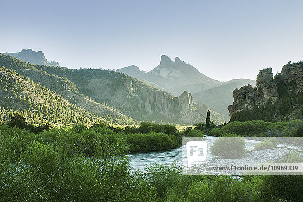 Die frühe Morgensonne beleuchtet ein grünes Flusstal und scharfe Berggipfel; Argentinien .