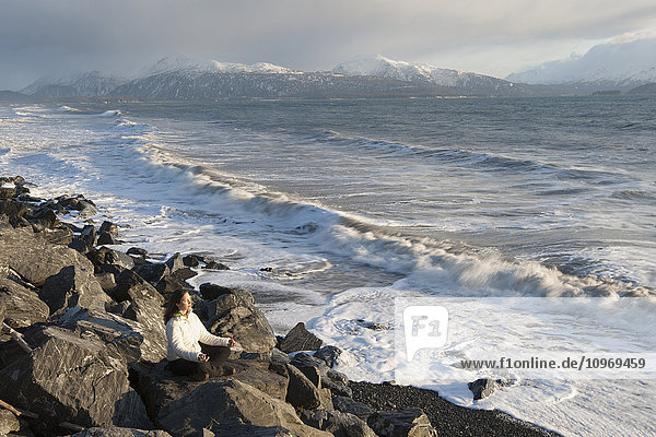 Woman practicing meditation on a rocky beach  Homer Spit  Southcentral Alaska