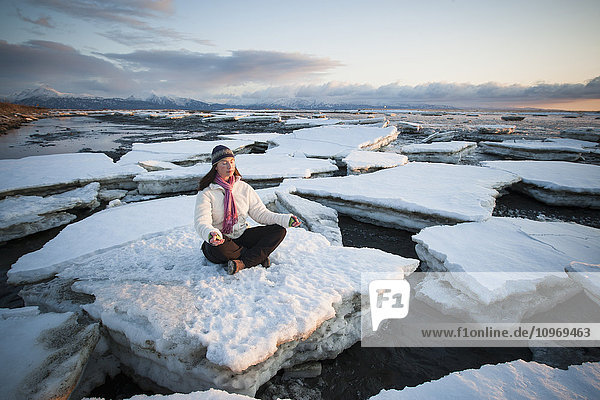 Frau übt sich in Meditation auf Eisbrocken  die auf der Homer Nehrung gestapelt sind  Süd-Zentral-Alaska