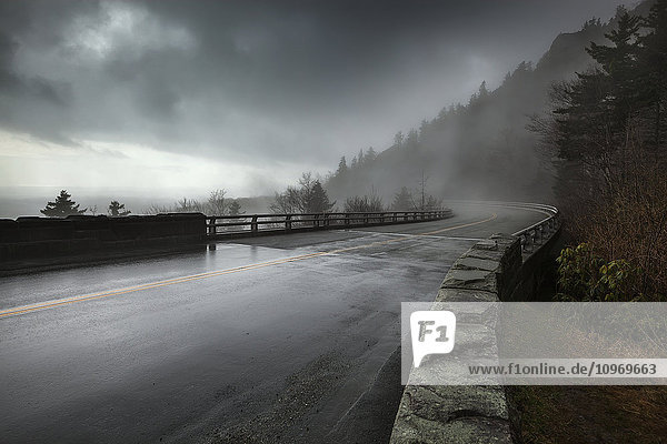 Regen auf einer nassen Brücke des Linn Cove Viaduct in North Carolina auf dem Blue Ridge Parkway mit stimmungsvollen  tief hängenden Sturmwolken und Nebel; North Carolina  Vereinigte Staaten von Amerika'.