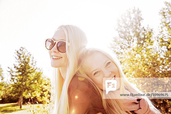 Zwei Schwestern  die im Herbst in einem Stadtpark Spaß haben und für die Kamera posieren; Edmonton  Alberta  Kanada'.