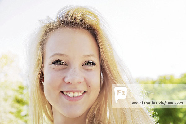 'Portrait of a beautiful young woman with long blond hair in a city park; Edmonton  Alberta  Canada'