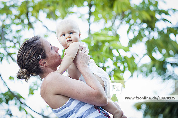 Eine Mutter hält ihr Baby  das nur eine Windel trägt  an einem warmen Tag; Fountain Valley  Kalifornien  Vereinigte Staaten von Amerika'.