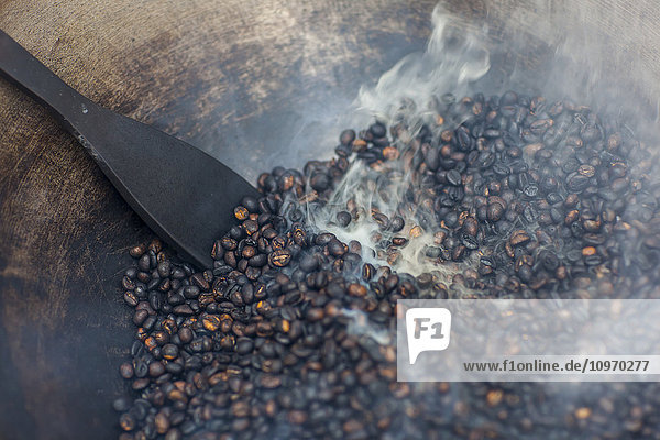 Kaffeebohnen werden von den Kaffeepflückern von Hand in einem Wok geröstet; Sumatra  Indonesien'.