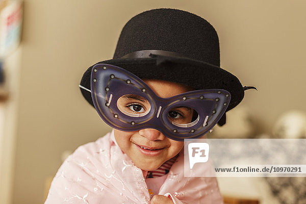 'Young girl playing dress up wearing a mask and hat; Edmonton  Alberta  Canada'