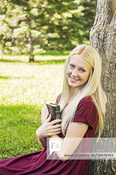 Eine junge Frau hält ihre Bibel dicht vor der Brust  während sie im Herbst in einem Park eine persönliche Andacht hält; Edmonton  Alberta  Kanada'.