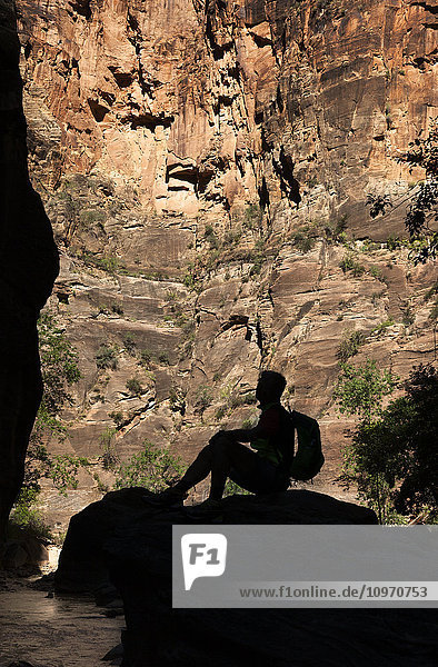 Der Schatten eines Mannes  der mit einem Rucksack auf einem Felsen sitzt und nach oben schaut  Bryce Canyon National Park; Utah  Vereinigte Staaten von Amerika'.