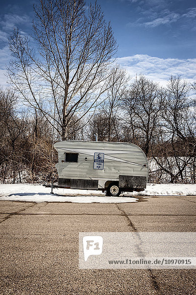 'An old trailer parked in a parking lot with traces of snow; Echo Lake  Saskatchewan  Canada'
