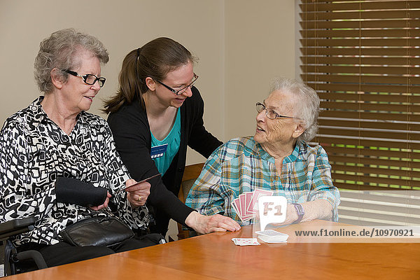 'Senior citizens and caregiver playing cards in their shared residence; Edmonton  Alberta  Canada'