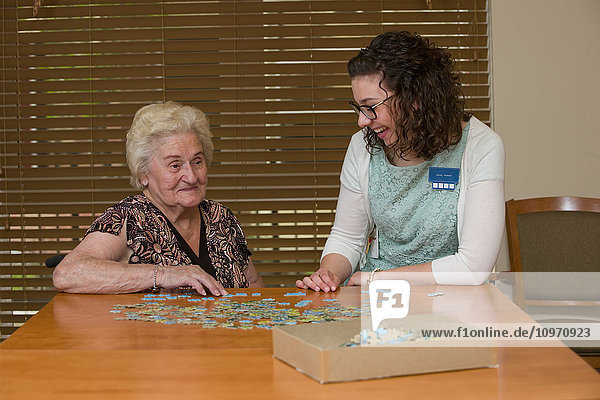 'Senior citizen and caregiver building a puzzle; Edmonton  Alberta  Canada'