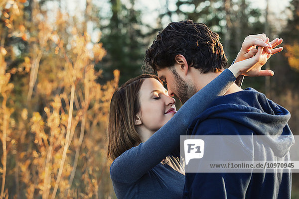 Ein junges Paar hält sich eng umschlungen und küsst sich in einem Park im Herbst; Edmonton  Alberta  Kanada'.