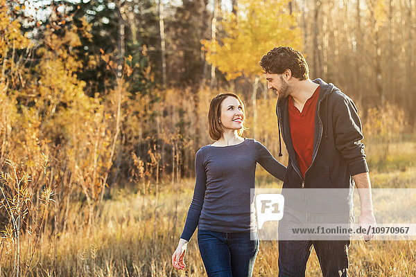 'A young couple walking and enjoying each other's company in a city park in autumn; Edmonton  Alberta  Canada'