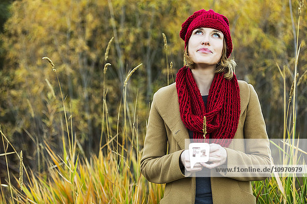 Eine schöne junge erwachsene Frau ist sehr nachdenklich während eines Ausflugs in einem Stadtpark im Herbst; Edmonton  Alberta  Kanada